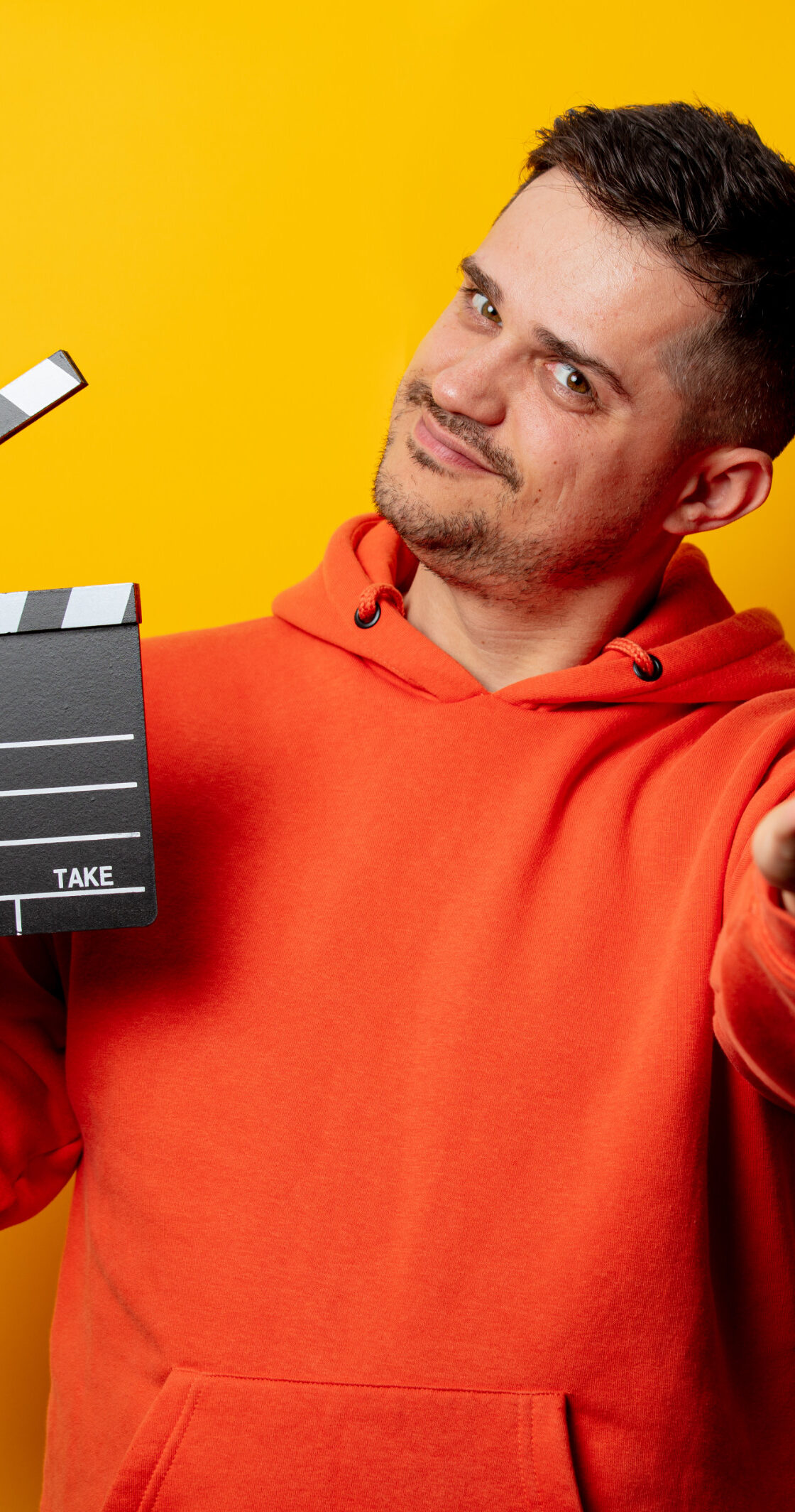 Mężczyzna trzymający klapkę kinematograficzną na żółtym tle | Agencja castingowa OBSADOWI